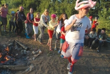 Volunteers and children celebrate around a fire at summer camp